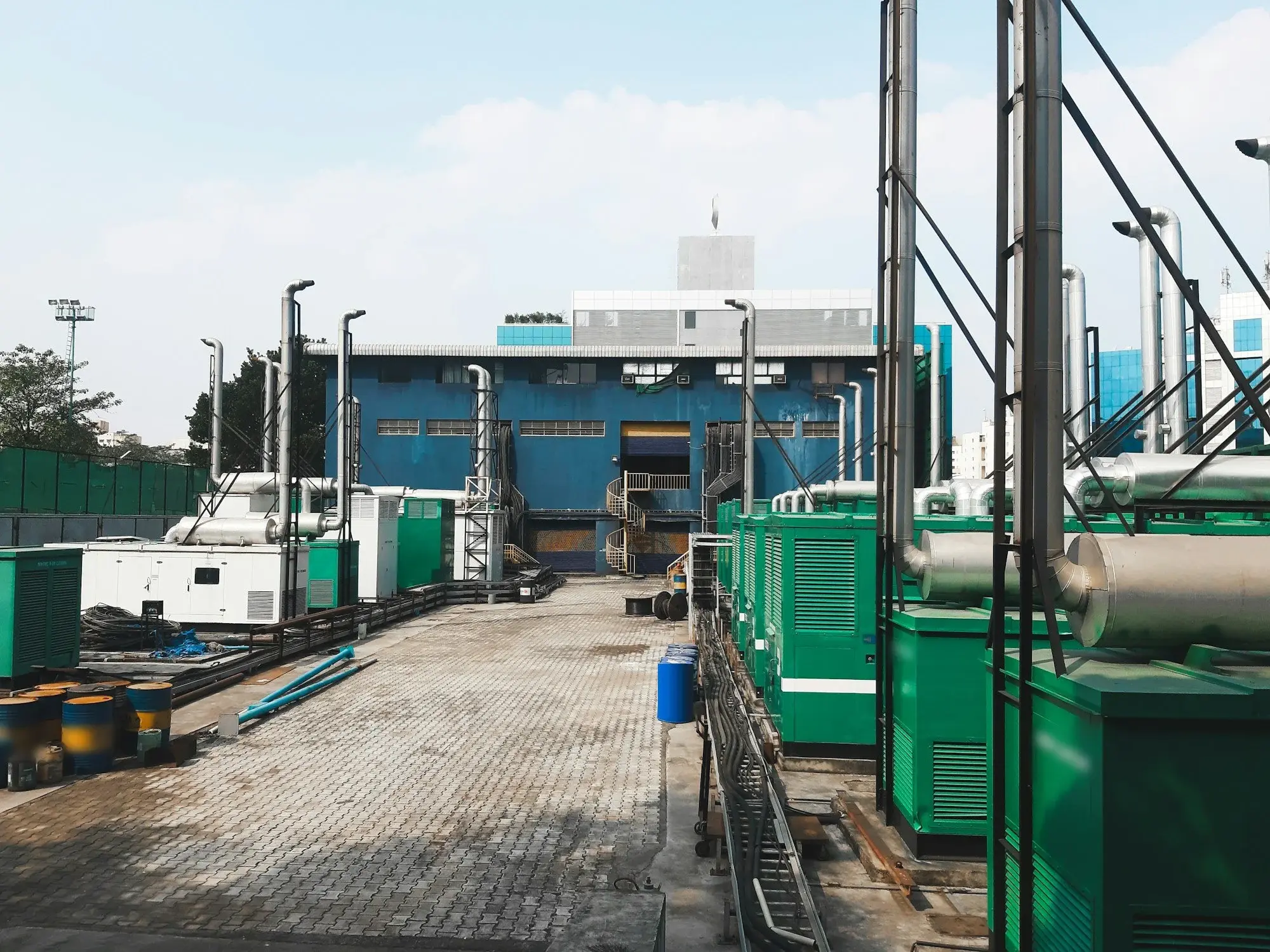 Central de grupos geradores a diesel em contêineres com chaminés de escape, ao lado de um prédio