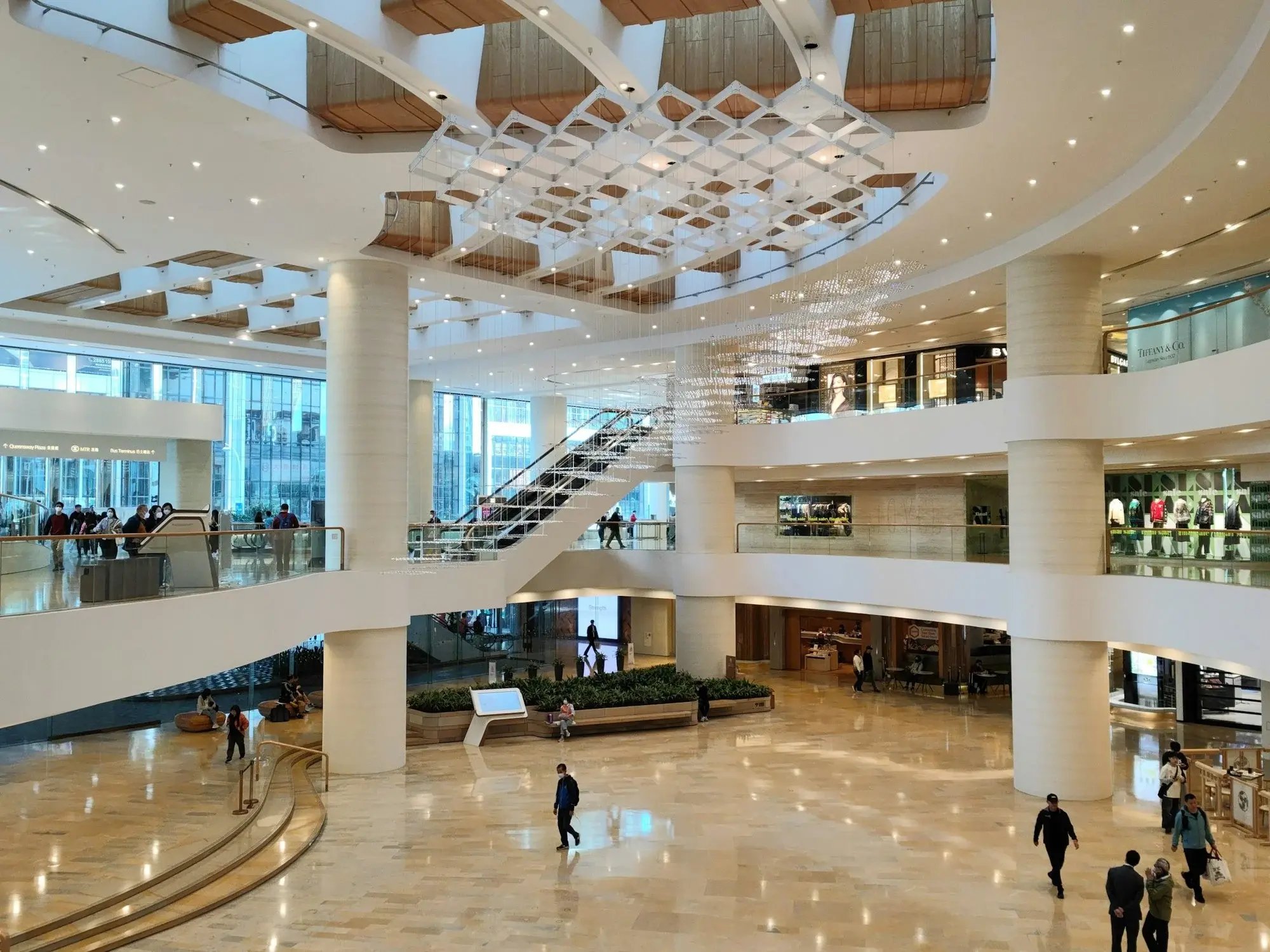 Átrio de um shopping center com escadas, pisos de circulação e público caminhando